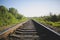 Rail tracks in the green field. Railway transport industry. Empty road on summer day. Travel lifestyle motivation photo