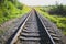 Rail tracks in the green field. Railway transport industry. Empty road on summer day. Travel lifestyle motivation photo