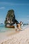 Railay Beach Krabi Thailand, couple walking in the morning on the beach with tropical cliffs and long tail boats on the