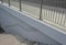 Railing at the bridge with vertical fence bars anchored to the ground with four concrete screws. plastic caps