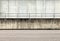 Railing on a grunge concrete wall dividing an asphalt road from a concrete building.