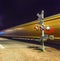 Railroad crossing with passing train by night