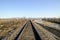 Railroad and depressive landscape with dry grass, swamp and blue sky