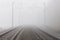 A railroad going into fog in the middle of an autumn landscape.