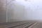 A railroad going into fog in the middle of an autumn landscape.