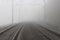 A railroad going into fog in the middle of an autumn landscape.