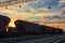 Railroad infrastructure during beautiful sunset and colorful sky, railcar for dry cargo, transportation and industrial concept