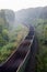 Railroad landscape. Empty freight train going at full speed among green trees in morning mist