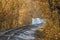 Railroad single track and railroad bridge through the woods in autumn. Fall landscape