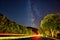 Railroad surrounded by trees underneath a starry night