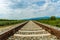 Railroad tracks leading to endless infinity. Meadow landscape and distant mountains.