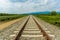 Railroad tracks leading to endless infinity. Meadow landscape and distant mountains.