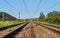 Railroad tracks, some plants growing between ties, low angle view, blurred countryside background