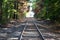 Railroad tracks in the woods leading to bright light