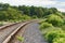 Railroad turns among the green trees in the summer