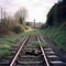 Rails and sleepers, the railway leads to a grave mound with a cross. Life finiteness concept
