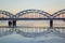 Railway bridge over frozen river in snowy winter Riga during sun