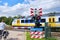 Railway crossing with barriers and blinking red lights and unsharp high speed train. Dutch text,Wait till red light is gone,