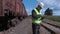 Railway employee using smart phone near wagons