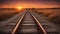 railway in the morning train track that leads to a bright orange sunset over the horizon.