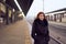 Railway station. Beautiful girl is standing on platform and waiting for train. Woman travels light