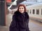 Railway station. Beautiful girl is standing on platform and waiting for train. Woman travels light