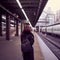 Railway station. Beautiful girl is standing on platform and waiting for train. Woman travels light