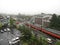 Railway station, red train, car park, building and streets at the Japanese countryside