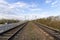 Railway at sunrise. Industrial landscape with railroad, colorful blue sky with red clouds, sun, trees and green grass