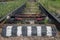 Railway switchboard with electric drive and red rod fixed on resinous sleepers, with chipping bar in black and white stripes.