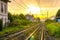 Railway tracks with old buildings on sides, wires above and Tuscany hills and mountains with dramatic cloudy yellow orange sky bac