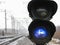 Railway traffic light shows blue signal on railway on cloudy day.