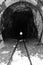 Railway tunnel with train at the end black and white. Locomotive at the end of tunnel monochrome.Rock vintage tunnel.