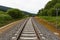 A railway turns upright through the spring green field. The sky is brightly blue with some white clouds