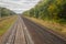 Railway. View from the window of the last train car or from the cab. Russian autumn landscape. Railway rails and sleepers