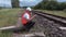 Railway worker on walkie talkie sitting near the rails