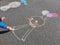 Rain chasing doll kid drawing with colourful pastel sidewalk chalks on the pavement