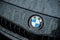 rain drops on BMW logo on black car front parked in the street