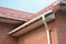 Rain gutter pipe system. Close up on Brick house with roof tiles and plastic roof gutter pipes drain. Guttering. Roofing