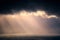 Rain on the sea with stormy clouds and sun rays