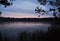 Rain at the sunset on the lake shore. Reeds on the coast. Summer rural landscape