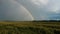 Rainbow above wheat field. Ripe crop field after rain and colorful rainbow in background rural countryside. Aereal dron shoot.
