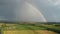 Rainbow Above Wheat Field.  Ripe Crop Field After Rain and Colorfull Rainbow in Background Rural Countryside. Aereal Dron Shoot.