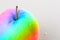 Rainbow apple close-up with water drops on a white background