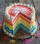 A rainbow cake with a slice missing
