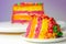 Rainbow celebration cake, coloured sponge cake filled and covered with frosting and hand decorated with chewy fruit candies in a