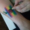 Rainbow and cherry painted face painting on a human hand