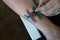Rainbow and cherry painted face painting on a human hand