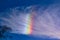 A rainbow cloud against a blue sky, a rare optical phenomenon in the atmosphere