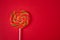 Rainbow color lollipop hard caramel on the stick on red background. Copy space. Top view